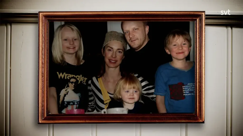 Stiligt - Ett inramat fotografi av två vuxna och tre barn som poserar och ler tillsammans inomhus.