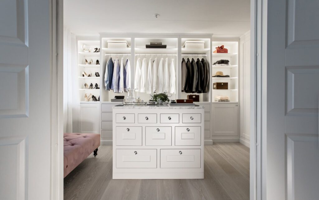 A white walk-in closet with a pink sofa.