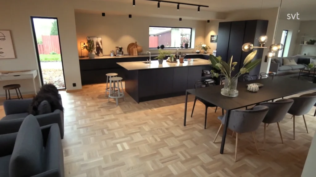 Stiligt - Modernt kök och matplats i öppen planlösning i Hjärup - Husdrömmar stil, med svarta skåp, ljust parkettgolv, stor ö och minimalistisk inredning.