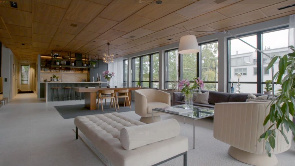 Stiligt - Modernt vardagsrum och matplats i öppen planlösning i Lidingö – Grand Designs-stil, med stora fönster, neutral inredning, ett stilrent kök i bakgrunden och frodiga växter vid fönstret.