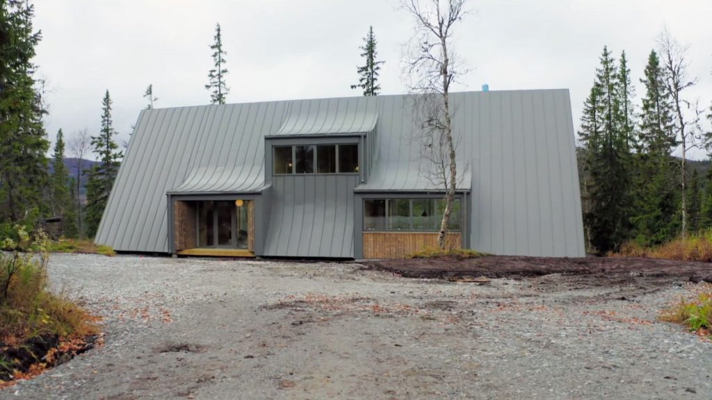 Stiligt - Ett modernt hus i Åre med ett brant, grått plåttak och trädetaljer, beläget bland träd – detta Grand Designs-inspirerade hem har en grusuppfart som leder upp till entrén.