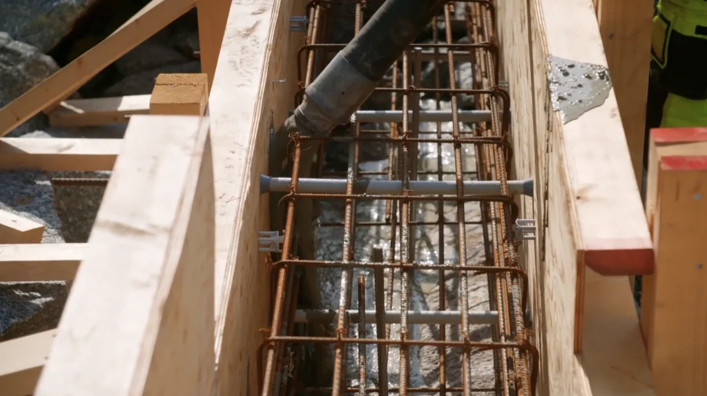 Stiligt - En närbild av betong som gjuts i en träform med ett armeringsjärn i metall på en byggarbetsplats i Österåker - Grand Designs.