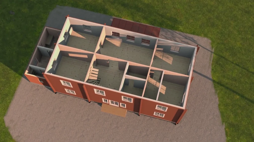 Stiligt - Flygfoto över ett Grand Designs-inspirerat enplanshus med röda ytterväggar, flera rum och stora fönster, beläget på en grustomt omgiven av gräs i Linköping.