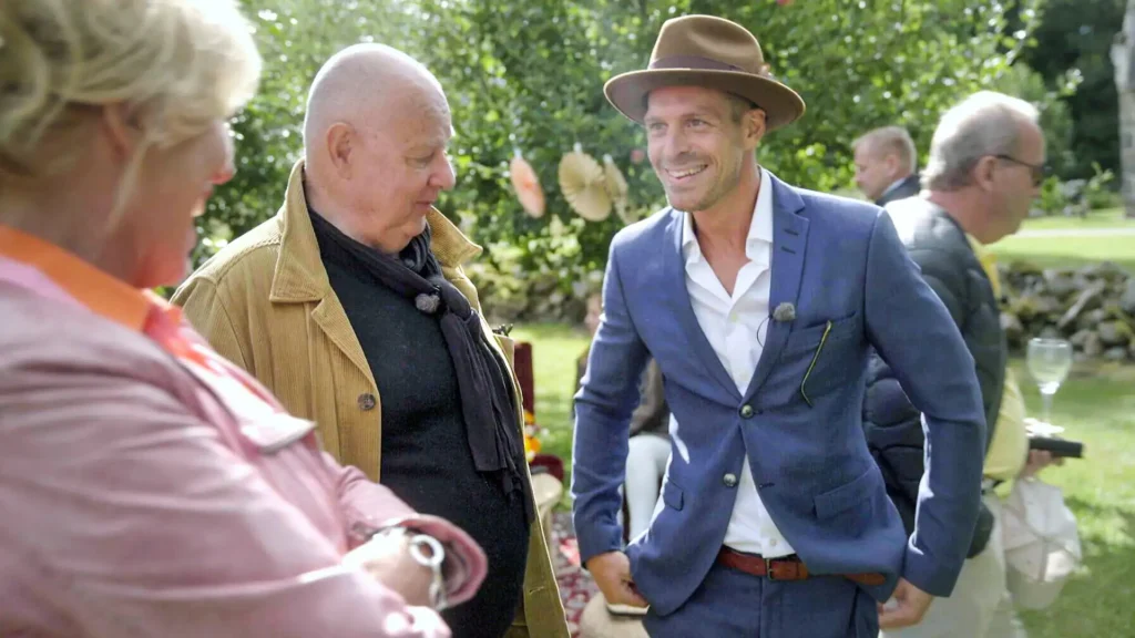 Stylish - In a suit and hat, a man talks to another man in a hat.