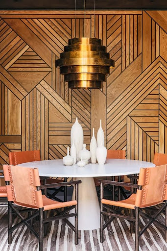 Stylish - A dining room with a wooden wall and bright orange chairs, with elegant interior design.