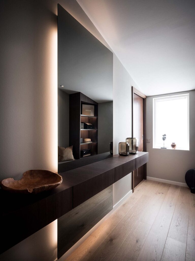 Stylish - Modern minimalist interior with a stylish large mirror, a wooden console, built-in shelves and a window. Natural light and neutral tones create a calm atmosphere.