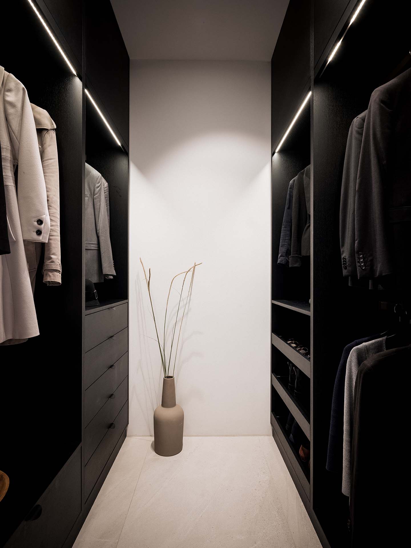 Stiligt - Stiligt minimalistisk Liten walk in closet hängjackor och en hög beige vas fylld med dekorativa gräs på golvet.