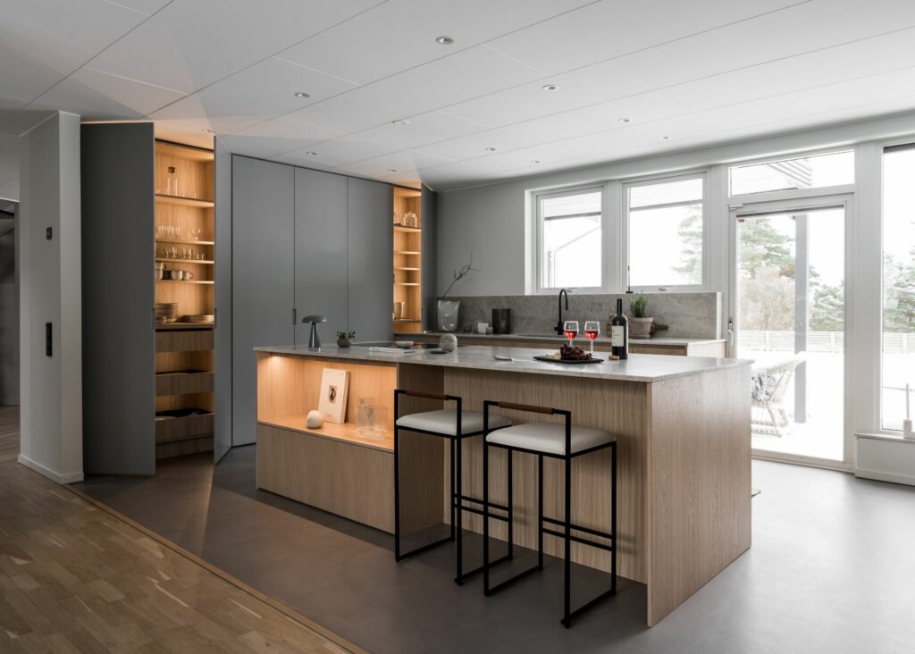 Stylish - A modern kitchen with a stylish center island, wooden cabinets, sleek bar stools, open shelves and large windows that flood the space with natural light.