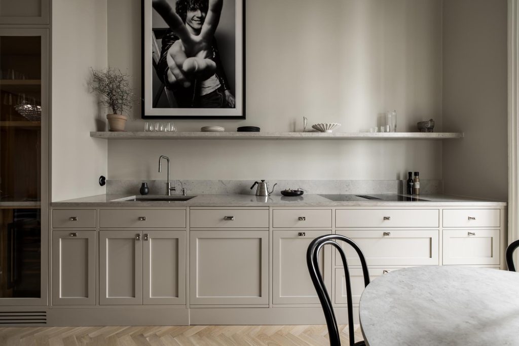 Stylish - A stylish minimalist kitchen features bright cabinets, wall shelves and a round table. A striking black and white photo is displayed above the counter.
