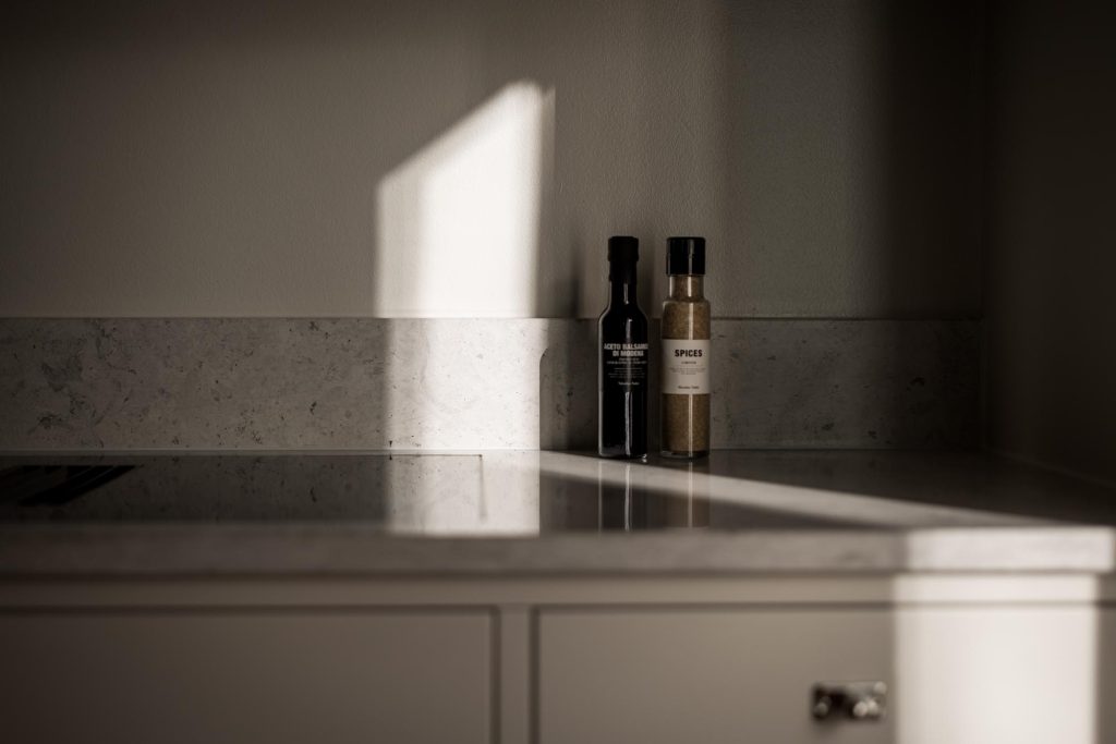 Stylish - Two stylish spice bottles sit on a kitchen counter, sunlight casting playful shadows across the surface.