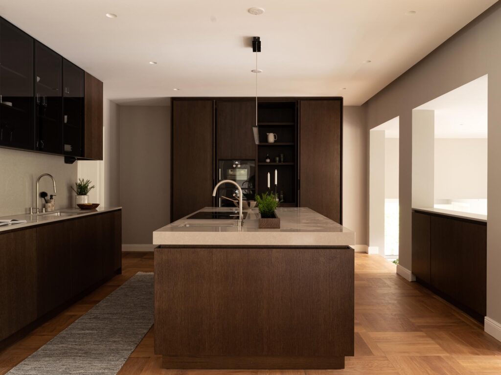 Stylish - Modern wooden kitchens with pocket doors, dark wooden shutters, large kitchen island with sink, light-colored countertops, black appliances and minimalist decor on wooden floors.