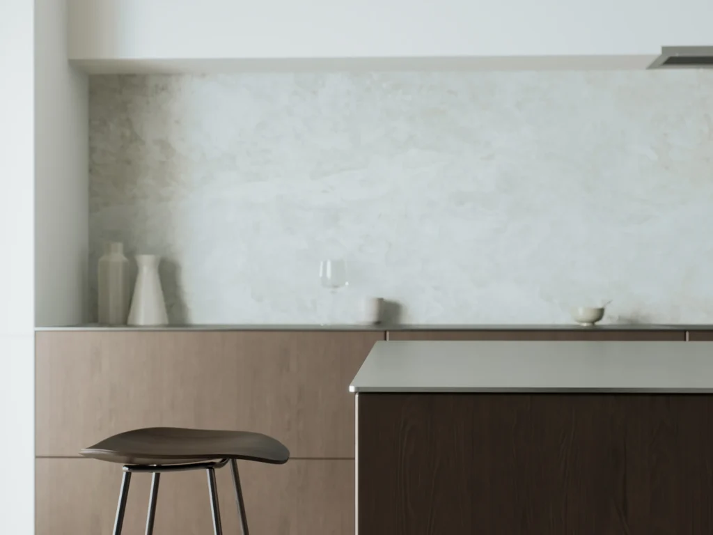 Stiligt - Minimalistiskt kök med en brun stol, ljusa träskåp och en vit bänkskiva till kök. Enkel inredning med två vaser, ett glas och en skål mot ett ljust stänkskydd.